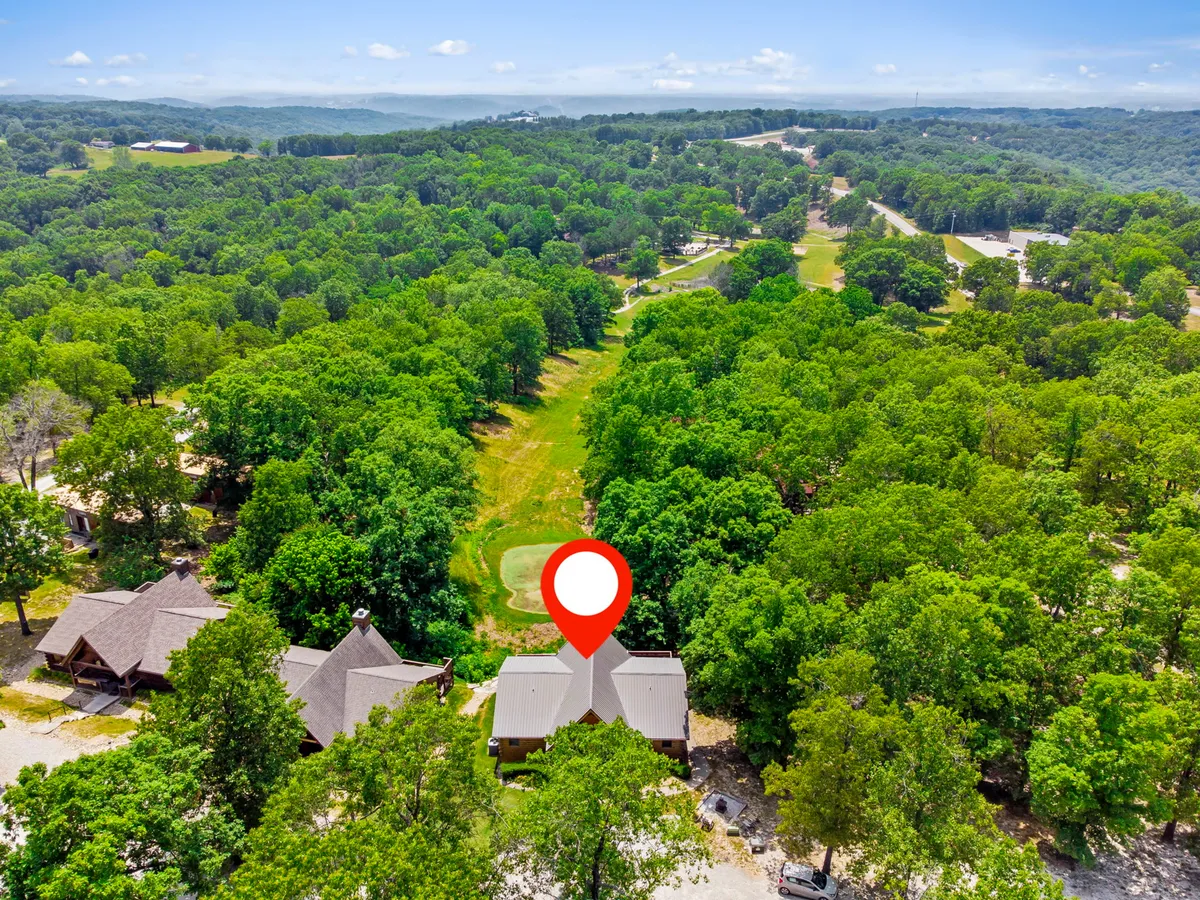 A relaxed outdoor scene featuring lush green trees, a well-maintained golf course, and rustic log cabins nestled at the edge. The natural landscape is inviting, perfect for both active pursuits and peaceful wildlife spotting.