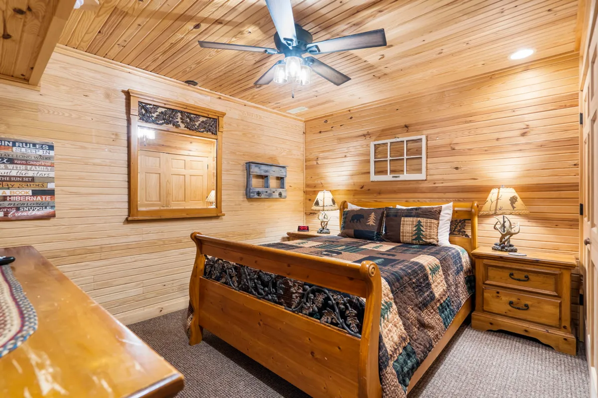 A warm and comfortable bedroom with a wooden bed, decorative quilt, nightstands with lamps, wooden paneling, and a mirror. The room exudes homeliness, inviting guests to unwind and enjoy private moments.