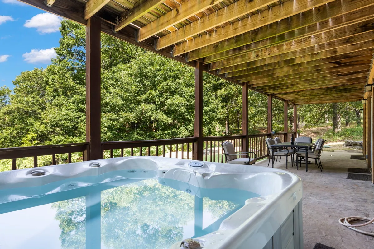 A tranquil outdoor seating area with a private hot tub set amid lush greenery. The space is designed for relaxation, offering a perfect spot to unwind after a day of outdoor adventure, with views of nature all around.